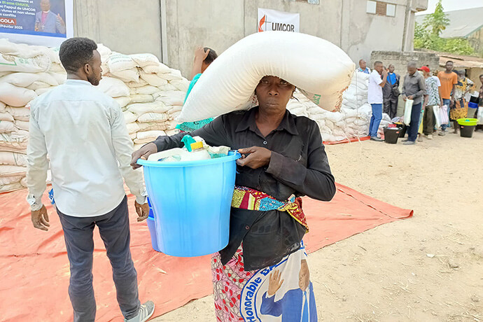 Mme Matshozi Fatuma porte un sac de nourriture sur sa tête sur le site de distribution à Kisangani, Congo. Grâce à un financement de 150 000 dollars de UMCOR (United Methodist Committee on Relief), l'Église Méthodiste Unie a aidé plus de 10 000 personnes déplacées, soit 1 600 ménages, dans la région de Kisangani. Photo par Lebon Okito, UM News.