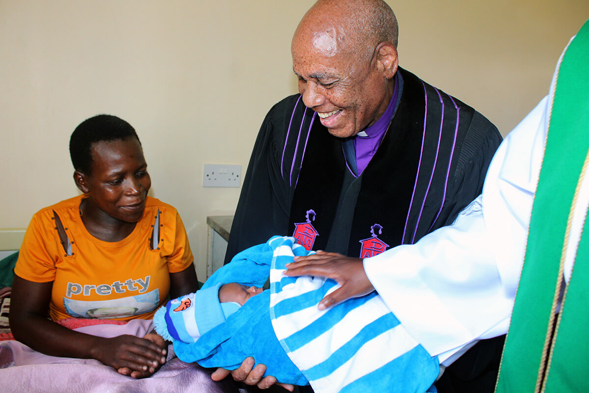 Bishop Eben K. Nhiwatiwa holds newborn Clarence Rinomhota as his mother, Sarah Mushamba, looks on at Chindenga rural health clinic in Mutoko, Zimbabwe. The center, which was dedicated Feb. 22, is the final clinic under the United Methodist Nyadire Mission Hospital to be renovated. Photo by Kudzai Chingwe, UM News.