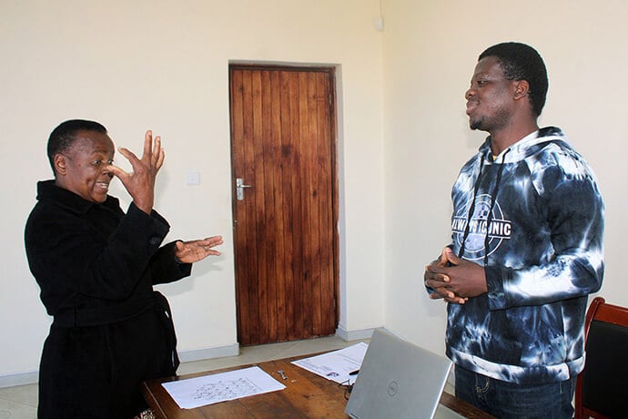 Le "pasteur Collins" Kwasi Prempeh (à droite) communique avec Spiwe Mhere, un interprète en langue des signes, au bureau principal de l'Église Méthodiste Unie à Mutare, au Zimbabwe, en mai. Prempeh vise à favoriser un culte inclusif, où la langue des signes est utilisée et célébrée, en particulier dans le ministère des enfants. Photo par Kudzai Chingwe, UM News.