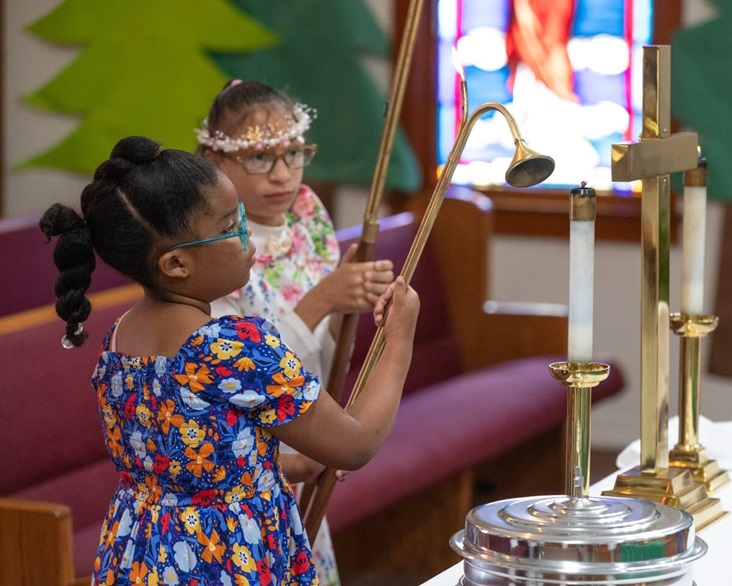 Accolytes Janae Williams (left) and Espn’ian Keys extinguish the candles following worship Hartzell Mt. Zion United Methodist Church in Slidell, La. Photo by Mike DuBose, UM News.