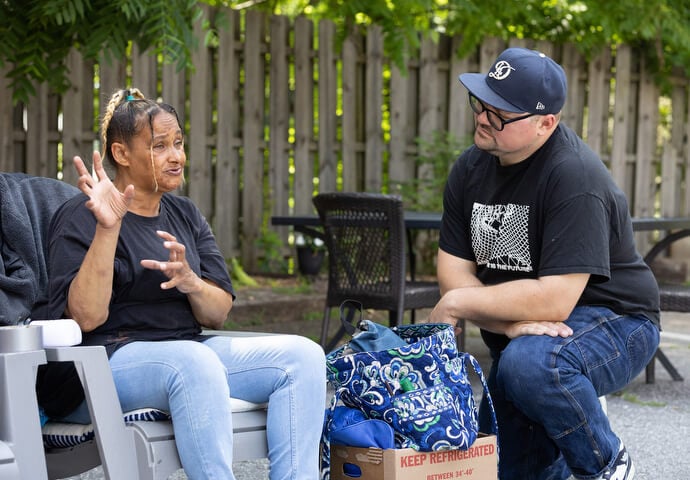 The Rev. Dustin Mailman (right) visits with the mother of a worker at Deep Time. She was having trouble with transportation and Mailman was trying to help her think through her options for an inexpensive car.