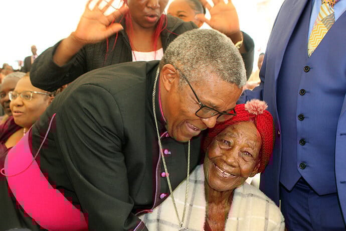 Centenarian Janet Gowe smiles as she receives a hug from Bishop Malusi Mpumlwana from the Ethiopian Episcopal Church in South Africa during the dedication of United Methodist Nzira Sanctuary in Murewa, Zimbawe. Photo by Kudzai Chingwe, UM News.