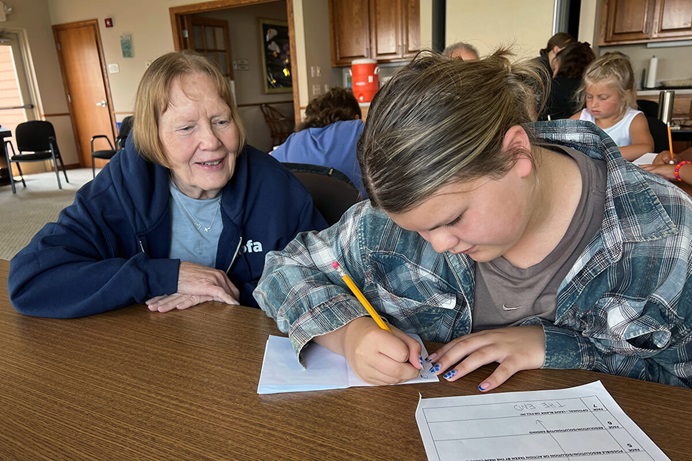 Donnette Gering helps her granddaughter Amelia Polreis write a story as part of Grandparents and Me Camp at Lake Poinsett in Arlington, South Dakota. Photo by Lilla Marigza, UM News. Donnette Gering helps her granddaughter Amelia Polreis write a story as part of Grandparents and Me Camp at Lake Poinsett in Arlington, South Dakota. Photo by Lilla Marigza, UM News.