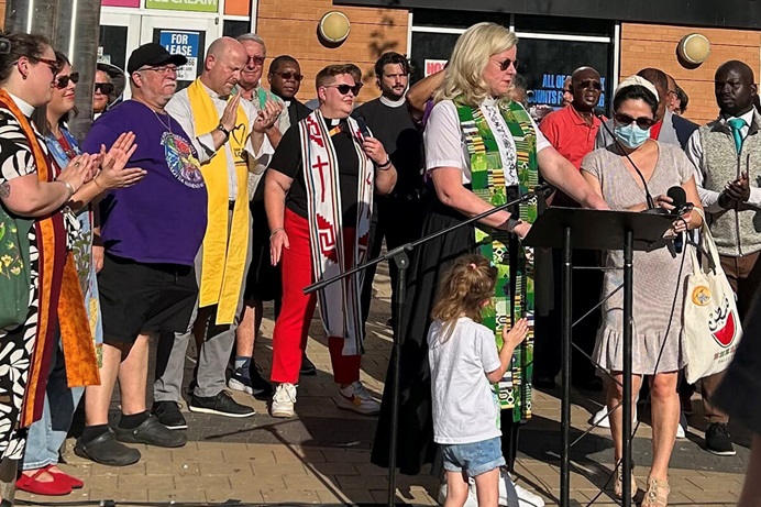 Unos 40 líderes religiosos/AS de todo Washington, D.C., se unieron el 22 de agosto para liderar una vigilia de oración en Columbia Heights, un barrio étnicamente diverso. El grupo buscaba presentar una visión de unidad y esperanza ante el despliegue de tropas de la Guardia Nacional por parte de Trump en la capital del país. En el centro, con la estola verde y blanca, se encuentra la Revda. Donna Claycomb Sokol, pastora de la Iglesia Metodista Unida Mount Vernon Place, quien habló en el evento. Foto de Sharon Groves, del Festival Center. Unos 40 líderes religiosos/AS de todo Washington, D.C., se unieron el 22 de agosto para liderar una vigilia de oración en Columbia Heights, un barrio étnicamente diverso. El grupo buscaba presentar una visión de unidad y esperanza ante el despliegue de tropas de la Guardia Nacional por parte de Trump en la capital del país. En el centro, con la estola verde y blanca, se encuentra la Revda. Donna Claycomb Sokol, pastora de la Iglesia Metodista Unida Mount Vernon Place, quien habló en el evento. Foto de Sharon Groves, del Festival Center.