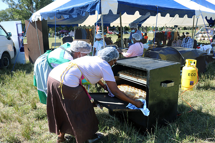 Members of Divine Grace Bakery remove buns from a gas oven at a Chitungwiza Marondera District business expo as they showcase their newly acquired baking skills. Funded by a United Women in Faith grant, Divine Grace Bakery is designed to financially empower women through baking. Photo by Eveline Chikwanah, UM News.