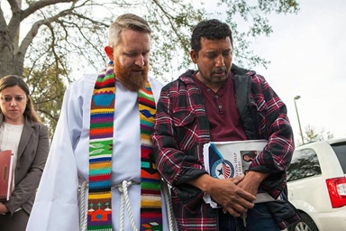 El Rev. Andy Oliver a la izquierda, de la Iglesia Metodista Unida de Allendale en San Petersburgo, Florida ora con Luis Blanco frente a la oficina de inmigración de Tampa el 30 de enero de 2018. La congregación apoyó a Blanco y a su familia durante su proceso de deportación. Oliver continúa ministrando a las comunidades marginadas de Florida, incluyendo la organización de protestas semanales en centros de detención del estado que albergan a presuntos/as inmigrantes indocumentados/as. Foto de archivo cortesía del Rev. Andy Oliver. El Rev. Andy Oliver a la izquierda, de la Iglesia Metodista Unida de Allendale en San Petersburgo, Florida ora con Luis Blanco frente a la oficina de inmigración de Tampa el 30 de enero de 2018. La congregación apoyó a Blanco y a su familia durante su proceso de deportación. Oliver continúa ministrando a las comunidades marginadas de Florida, incluyendo la organización de protestas semanales en centros de detención del estado que albergan a presuntos/as inmigrantes indocumentados/as. Foto de archivo cortesía del Rev. Andy Oliver.