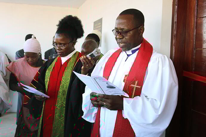 Bishop João Filimone Sambo, who leads the Mozambique-South Africa-Eswatini-Madagascar Episcopal Area, speaks during the July dedication of Muhalaze United Methodist Church’s new permanent chapel. At left is the Rev. Victoria Chifeche, Maputo District superintendent. Photo by Roque Facela, UM News.
