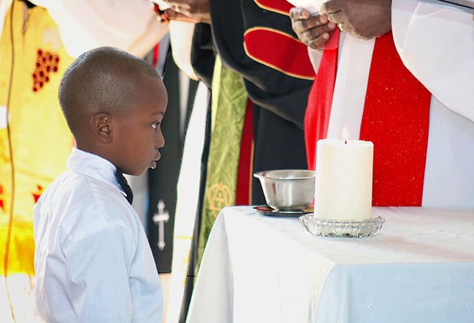 Glayson Principe Uasse stands at the front of the church to be baptized by Bishop João Filimone Sambo during Muhalaze United Methodist Church’s dedication in July. Photo by Roque Facela, UM News.