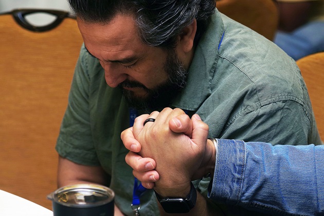 El Rev. Ismael Ruiz Millán, Director de Ministerios Conexiónales de la Conferencia Anual de Carolina del Norte, toma la mano de otro participante para orar e interceder por las necesidades mutuas durante el culto de clausura. Foto Rev. Gustavo Vasquez, Noticias MU. 