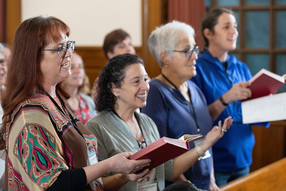 Participantes en la Reunión de Diáconos/as de La Iglesia Metodista Unida de 2025 cantan durante el culto inaugural en la Capilla del Aposento Alto en Nashville, Tennessee. De izquierda a derecha están las reverendas Shannon Howard, Tina Marie Rees y Sherry Brady, junto a Candace Brady. La nueva autoridad sacramental de los/as diáconos/as, aprobada en la Conferencia General del año pasado fue tema central del evento. Foto: Mike DuBose, Noticias MU.