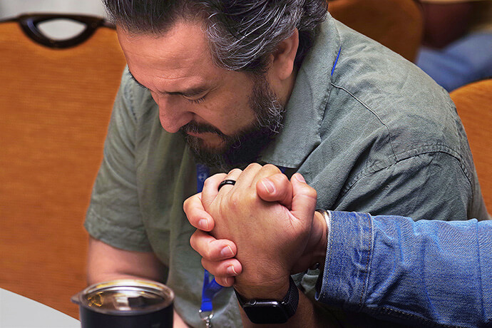 The Rev. Ismael Ruiz Millán, director of connectional ministries for the North Carolina Conference, takes the hand of another participant to pray and intercede for each other's needs during the closing service at MARCHA’s annual meeting Aug. 3 in Chicago. Photo by the Rev. Gustavo Vasquez, UM News.