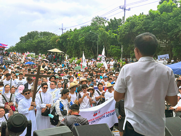 Retired Filipino Bishop Rodolfo A. Juan (foreground) speaks before a large crowd of protesters during the Trillion Peso March at EDSA People Power Monument in Quezon City, Philippines. He urged participants to pursue “righteousness and justice.” Photo courtesy of Blessy Grace De Leon.