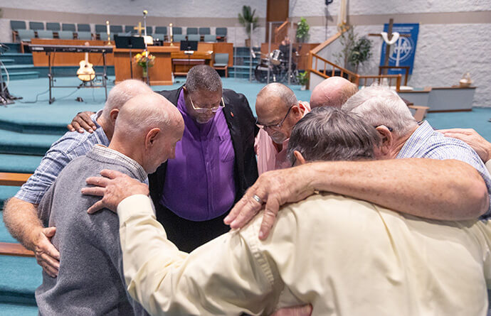 Bishop Frank Beard (center) prays with men from Elkhart Faith United Methodist Church before worship. Photo by Mike DuBose, UM News.