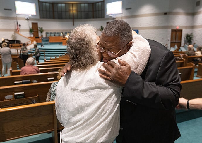 Vicki Bridensstein (left) hugs Bishop Frank Beard before worship at Elkhart Faith United Methodist Church. She says she has known Beard since he was a teenager. Photo by Mike DuBose, UM News.