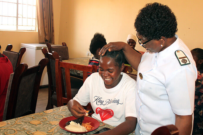 Sister Florence Mefor, a missionary with the United Methodist Board of Global Ministries and midwife, speaks with a patient enjoying lunch at Old Mutare Mission Hospital in Zimbabwe. Through Mefor’s work, the church’s mission hospitals have been providing daily meals for maternity patients. Photo by Kudzai Chingwe, UM News.