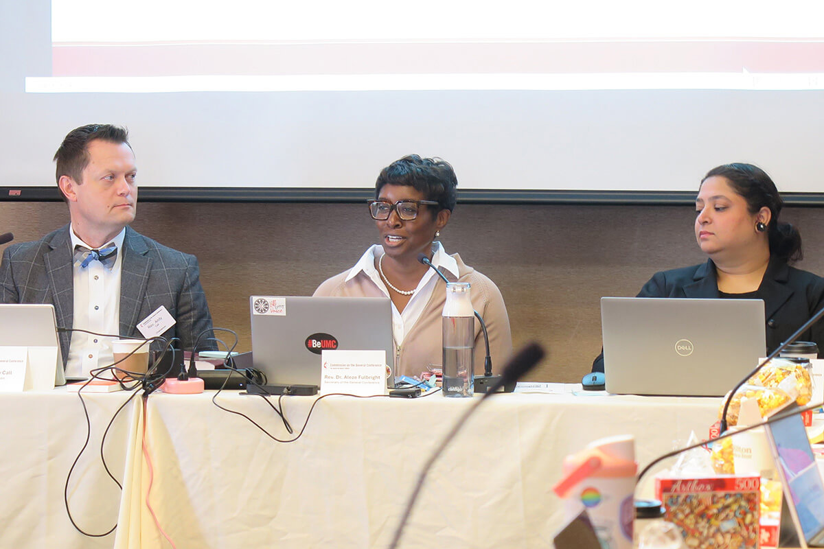 The Rev. Aleze M. Fulbright (center) celebrates the growth of The United Methodist Church in Africa as the Commission on the General Conference, meeting in Minneapolis on Nov. 11, considers setting the number of delegates for the 2028 General Conference. Sitting beside Fulbright, the General Conference secretary, are the Rev. Andy Call, the commission’s chair, and Sharah Dass, General Conference business manager. Photo by Heather Hahn, UM News.