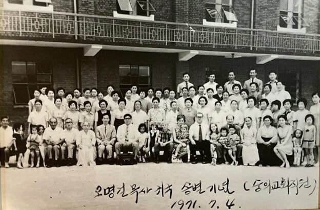 1971년 7월 4일, 조오지 오글(George E. Ogle) 목사가 박사학위를 마치기 위해 미국으로 떠나기 전, 소속 교회였던 인천 숭의감리교회에서 열린 송별회를 마치고 찍은 기념사진. 사진 속에는 조오지 오글(George E. Ogle) 목사와 도로시 오글(Dorothy L. Ogle) 선교사 부부가 함께 서 있으며, 오글 목사 옆에는 당시 감독이자 훗날 기독교대한감리회 감독으로 선출된 이호문 목사가 나란히 자리하고 있다. 사진 제공, 인천 숭의감리교회.