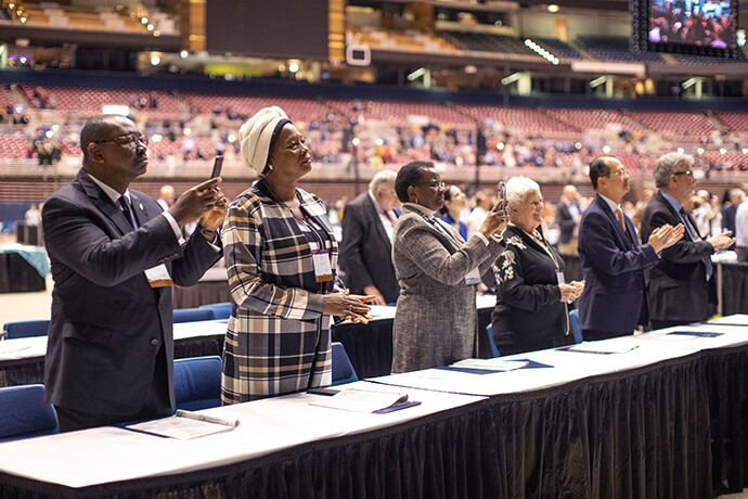 Members of the Judicial Council stand during the Feb. 23 day of prayer at the 2019 Special General Conference in St. Louis. (From left) N. Oswald Tweh, Sr., Lydia Romão Gulele, the Rev. J. Kabamba Kiboko, Deanell Reece Tacha, the Rev. Luan-Vu “Lui” Tran, and the Rev. Øyvind Helliesen. File photo by Kathleen Barry, UM News. 