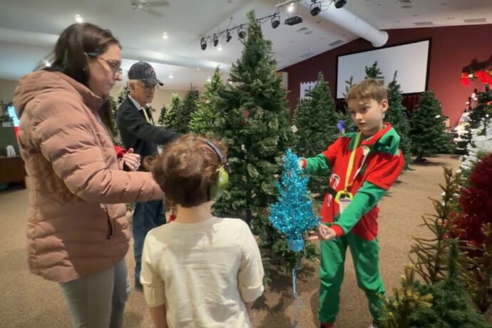 Volunteer Kalvin Davis helps a family select a tree from the artificial “tree farm” at Faith Community Church of Coopersville, Michigan, a United Methodist congregation. Video image by Lilla Marigza, UM News.