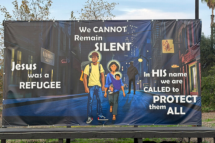 An illustration by artist Sonja Dotson at Claremont United Methodist Church in California portrays the Holy Family in a contemporary setting with a menacing figure hovering behind them. Jesus, Mary and Joseph are depicted with brown skin, representing their Middle Eastern origins, and the dark figure represents an agent from U.S. Immigration and Customs Enforcement. Photo courtesy of Claremont United Methodist Church.
