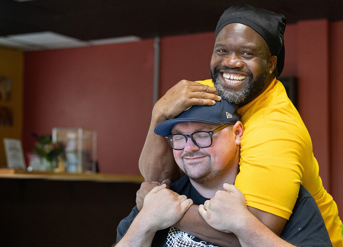 Timothy "GA" Underwood hugs the Rev. Dustin Mailman in the recently opened coffee shop at the Deep Time ministry. Underwood serves as minister of social enterprise for Deep Time and Mailman is its founding pastor. Photo by Mike DuBose, UM News.