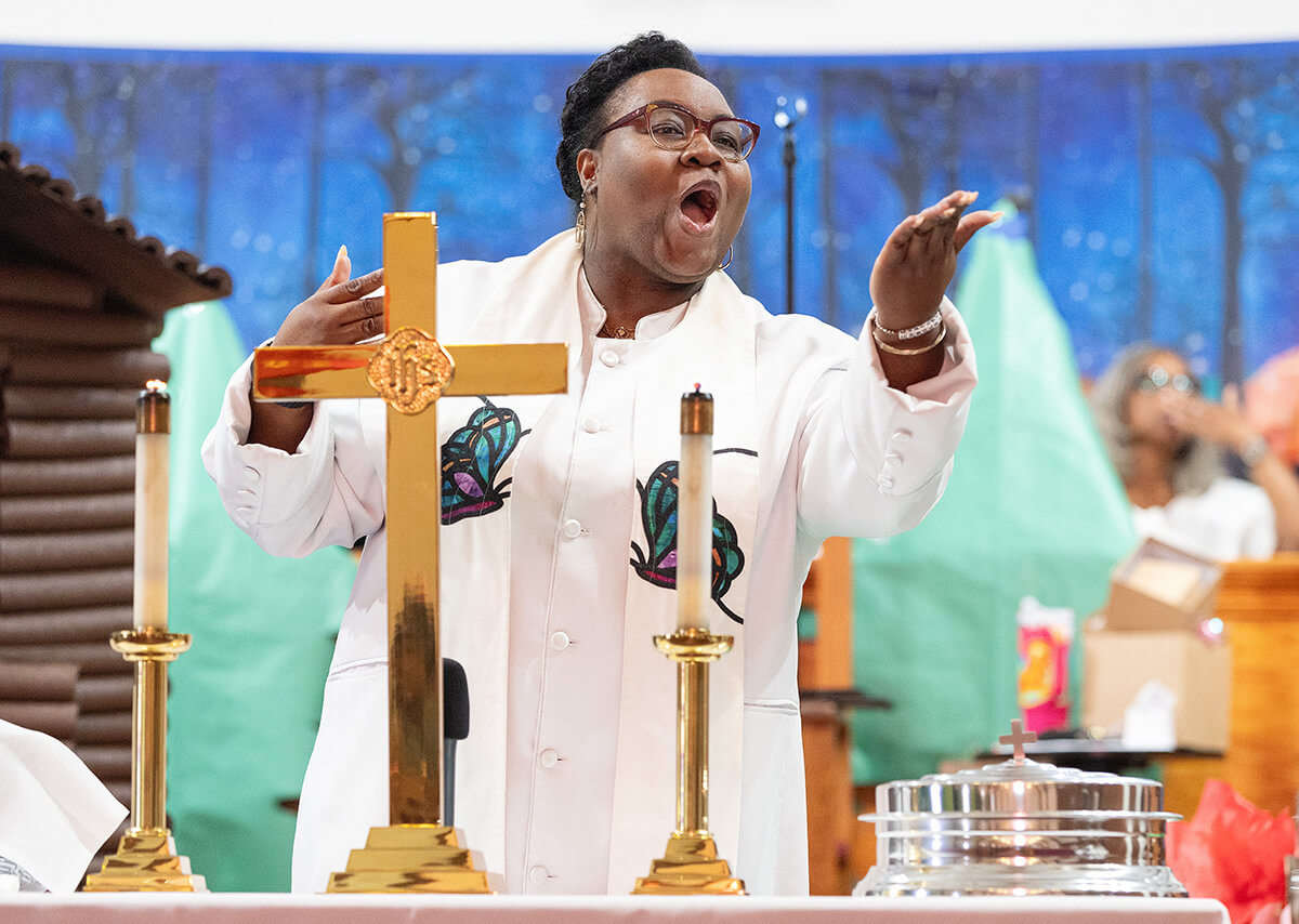 The Rev. Tiffanie Postell blows a kiss to parishioners as she prepares to bless the elements of Holy Communion at Hartzell Mt. Zion United Methodist Church in Slidell, La. Photo by Mike DuBose, UM News.