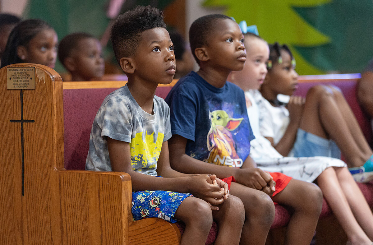 Children watch a video presentation during vacation Bible school at Hartzell Mt. Zion United Methodist Church. From left are Kobe Nichols, Kyree Nichols, Aspen Newberry and Landry O’neal. Photo by Mike DuBose, UM News.