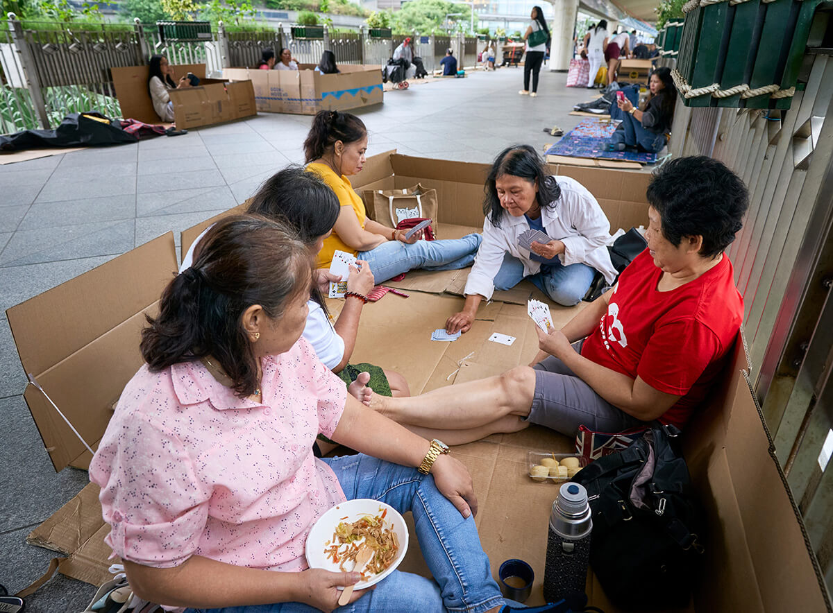 Migrant workers from the Philippines gather on Sundays in Hong Kong along Chater Road to relax, eat, and visit with their friends. Sunday is the only day off for most of the women, who work as domestic servants throughout the city. They often sit on cardboard that they rent for a few hours from Chinese women. Photo by Paul Jeffrey, UM News.