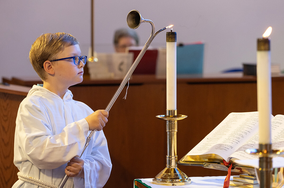 Acolyte Andersen Meyer lights the altar candles at St. Luke’s United Methodist Church in New Orleans. Photo by Mike DuBose, UM News.