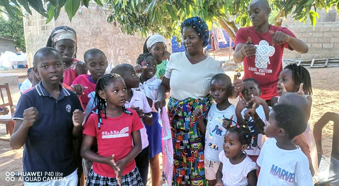 The Rev. Maria Matsinhe, a nurse and health coordinator for The United Methodist Church in Mozambique, interacts with children, including twins Paulo and Joana Buque (pictured at left), at Chucunja Elementary School in Morrumbene village. Matsinhe heads the church’s mobile clinic, which set up at the school to conduct health screenings. Photo by Antonio Wilson, UM News. 