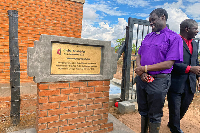 Bishop Gift K. Machinga admires a sign at Mikundi Dairy Farm in Mikundi, Malawi, after a dedication ceremony for the farm in November. The farm is supported by the United Methodist Board of Global Ministries’ Yambasu Agriculture Initiative. During his visit, Machinga led local church members in a time of prayer and emphasized that projects like Mikundi are the key to the church’s future. Photo by Francis Nkhoma, UM News.