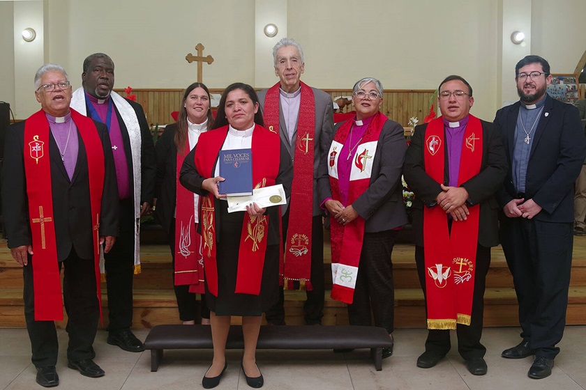 La Revda. Juana Jamileth Moncada Torres, muestra el Libro de Culto de La Iglesia Metodista Unida y el certificado de ordenación que, junto con la estola roja, conforman los tres símbolos ceremoniales que reciben quienes son ordenados/as como presbíteros/as de la iglesia. En la imagen de izquierda a derecha: Obispo Emérito José Roberto Peña Nazario, Obispo Juan Miguel Simpson Bennett, Revda. Amy Spaur, Obispo Rubén Sáenz Jr., Obispa Lizzette Gabriel Montalvo, Obispo Juan de Dios Peña y el misionero Cristian Schlick. Foto Rev. Gustavo Vasquez.