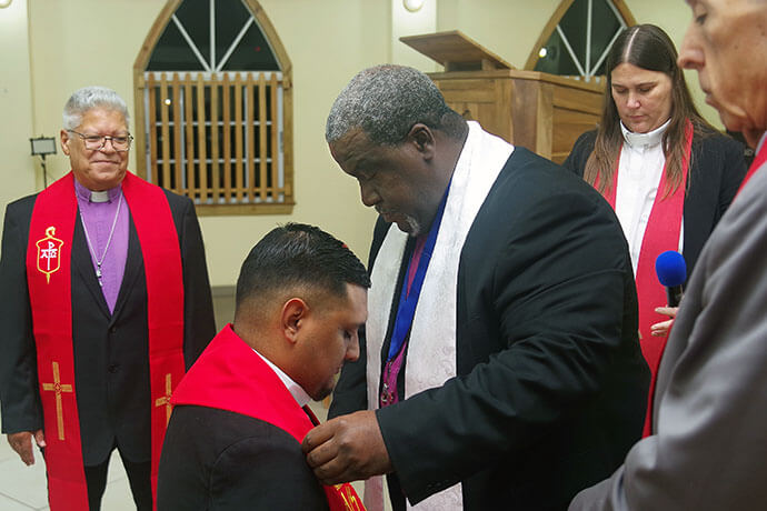Bishop Juan Miguel Simpson Bennett of the Methodist Church of the Americas and the Caribbean places the presbyteral stole, crafted by Honduran artisans, onto the Rev. Héctor Mauricio Rodríguez Laínez. Looking on (from left) are Bishop Emeritus José Roberto Peña Nazario, pastor of Central United Methodist Church of Danlí; the Rev. Amy Spaur, liaison for the Horizon Texas Annual Conference Board of Ministries and the United Methodist Mission of Honduras; and Bishop Rubén Sáenz Jr., episcopal leader of the mission. Photo by the Rev. Gustavo Vásquez.