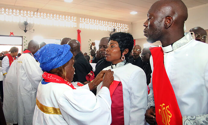 The Rev. Mwayuma Ayenda, a member of a delegation from the East Congo Episcopal Area, helps a new pastor put on her stole during the December ordination ceremony in Bangui, Central African Republic. An 11-person delegation traveled from Kindu, Congo, to spend 12 days training new United Methodist leaders, laity and youth in the country. Photo by Chadrack Tambwe Londe, UM News.  