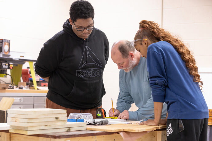 Vocational instructor Tim Queener (center) helps Zavean Graves (left) and Navaeh Chairs determine the center of a board as part of a training program in the Judge Dinkins Educational Center, housed at McKendree United Methodist Church in Nashville, Tenn.  Queener turned the routine carpentry exercise into a review on fractions. Photo by Mike DuBose, UM News.