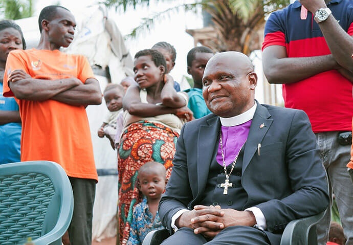 Bishop Nelson Kalombo Ngoy sits among community members during his pastoral visit to a camp for displaced people near Kalemie. His presence in the heart of the camps during the Christmas season demonstrates the United Methodist Church’s commitment to embodying a ministry of compassion and solidarity toward those who have lost everything, reminding survivors that they are neither forgotten nor alone in their suffering. Photo by Jenovic Mandandj, UM News.