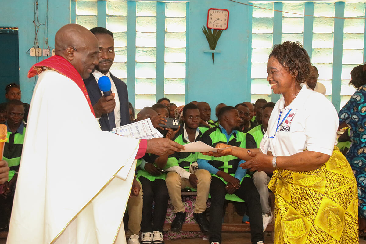 Lufula Charlotte, épouse d’un pasteur, sourit en recevant son certificat de formation des mains de l’Évêque Méthodiste Uni Antoine Kalema Tambwe lors d’une cérémonie officielle à Kindu. Lufula fait partie des plus de 60 épouses de pasteurs et de surintendants de district qui ont suivi ce programme, soutenu par le Conseil des Ministères Mondiaux de l'Église Méthodiste Unie, visant à renforcer leurs compétences en matière de leadership et de développement communautaire dans l'Est du Congo. Photo de Chadrack Tambwe Londe, UM News.