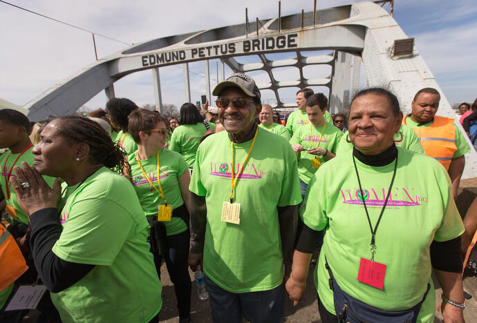 United Methodist Bishop Woodie W. White (center) crosses the Edmund Pettus Bridge in Selma, Ala., in 2015, during the 50th anniversary observance of the "Bloody Sunday" protest march seeking voting rights for African Americans. White brings students from his Candler School of Theology class on race relations to Selma each year. He is joined by his wife, Kim (right), Ruby Shinhoster of the Southern Christian Leadership Conference’s Women’s Organizational Movement for Equality Now (left) and Candler student Beth Clark.  File photo by Mike DuBose, UM News.