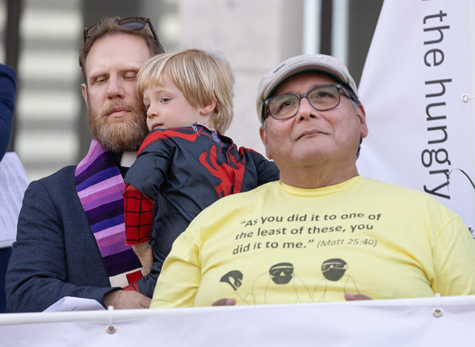 The Rev. Eric Mayle (left) holds his son, Séamus, 3, during the closing moments of Palm Sunday Witness in Nashville, Tenn. Mayle is pastor of Edgehill United Methodist Church in Nashville. At right is Patrick Camacho, a member of Edgehill.