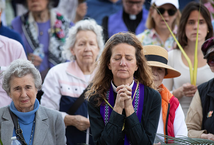 The Rev. Lissa Smith (center) prays during a Palm Sunday Witness near the Tennessee State Capitol in Nashville. Smith is an Episcopal clergywoman.