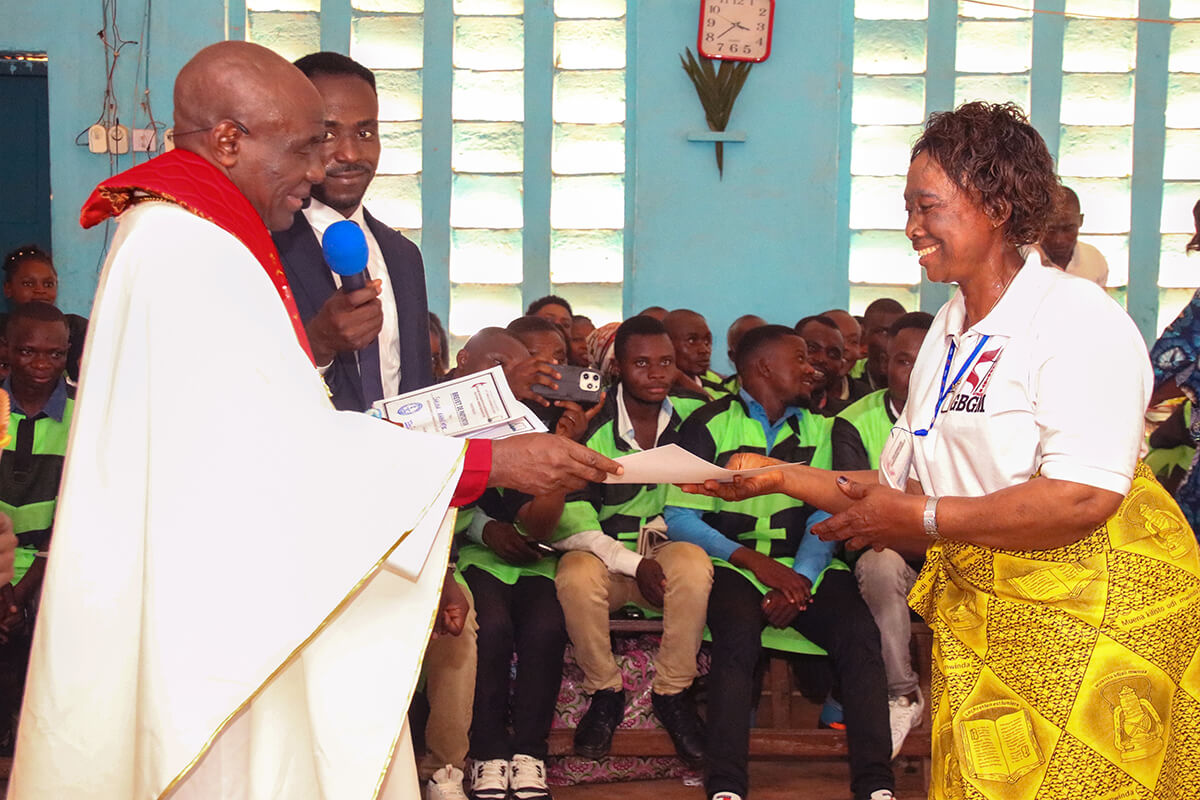 Lufula Charlotte smiles as she receives her training certificate from United Methodist Bishop Antoine Kalema Tambwe during an official ceremony in Kindu, Congo. Lufula is one of more than 60 pastors’ wives who completed a leadership program supported by the United Methodist Board of Global Ministries. Photo by Chadrack Tambwe Londe, UM News.