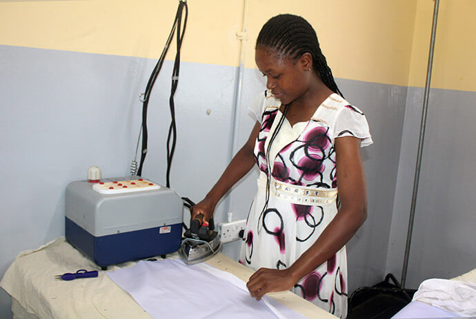 Endurance Gawa, an employee of Murewa High School in Murewa, Zimbabwe, uses a boiler iron to press a garment made in the school’s factory department. Photo by Kudzai Chingwe, UM News.