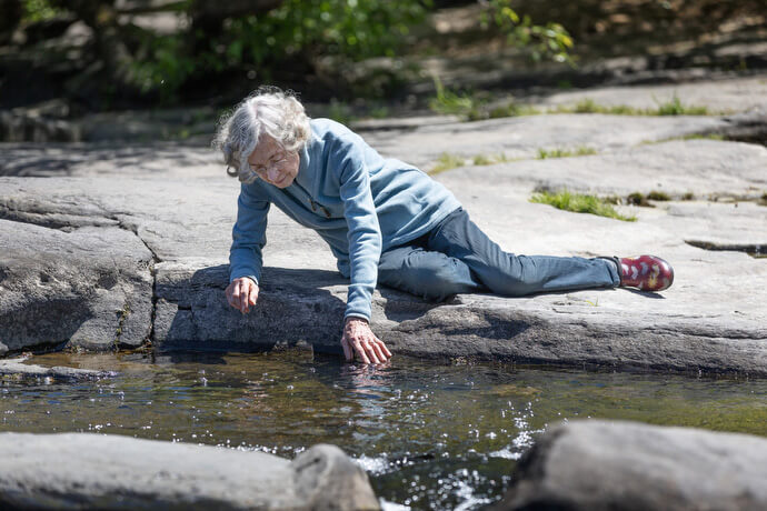 Mary Blom of Sebastopol (Calif.) United Methodist Church touches the water of Santa Rosa Creek during a Sacred Ground field trip to Bita-Kom-Tara (Flat Rock Park). 