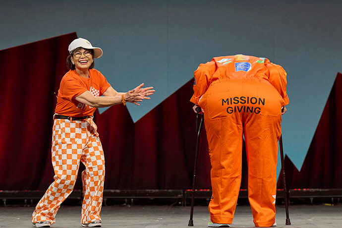 Sue Owens dresses as an Indy driver whose uniform shows mission-giving opportunities during the United Women in Faith Assembly in Indianapolis on May 16. Beside her is Marilyn Reid. Photo by Paul Jeffrey, United Women in Faith.
