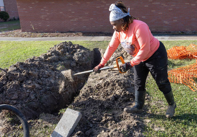 Crystal Latham fills a ditch she helped dig after repairing a leaky water pipe at an apartment complex in Gulfport, Miss. “I can do anything a man can do,” she said.