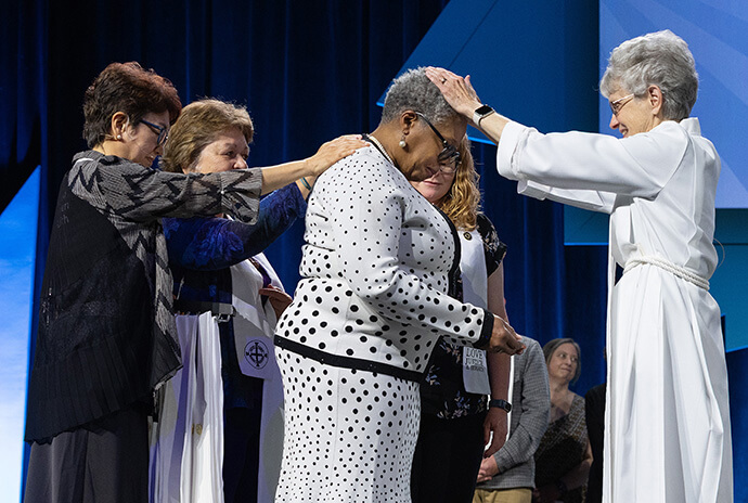 Yvonne Bouknight is consecrated as a deaconess by United Methodist Bishop Peggy Johnson (right) during the United Women in Faith Assembly 2026 in Indianapolis. At left is Sung-ok Lee of United Women in Faith. Photo by Mike DuBose, United Women in Faith.