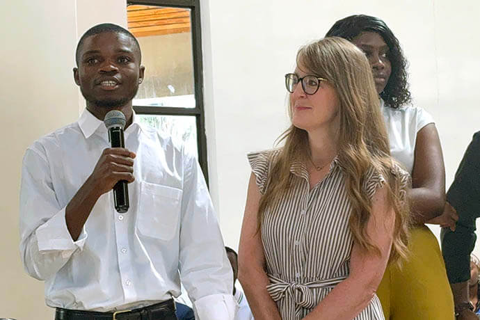 Isaac Sakala shares his personal testimony during worship service June 7 in the Kwang Lim Chapel on Africa University’s campus in Mutare, Zimbabwe, while Traci Jones proudly looks on. Jones and husband Mykal Jones traveled from Dallas to Zimbabwe to see Sakala, whom they sponsored for 10 years through Family Legacy’s Excel Beyond program for orphans and disadvantaged children and youth. Photo by Eveline Chikwanah, UM News.