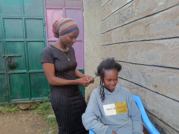 Church member Jackline Mwende, who leads the No Girl No Cry initiative, braids Vivian Kadzo’s hair at Parkview Kitengela United Methodist Church. Photo by Gloria Kache. 