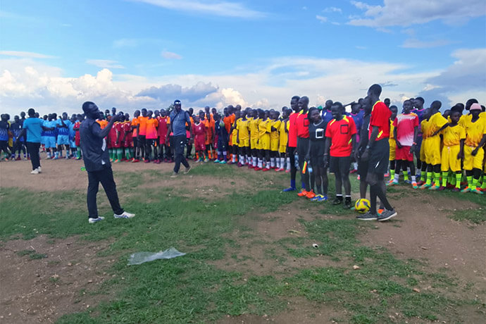 Teams line up at Imvepi Settlement’s central grounds during the launch of The United Methodist Church’s Kick Out HIV tournament in Uganda. Participants say the competition helped to build bridges between refugees and their host communities. Photo by Juma Denis Daniel, UM News.