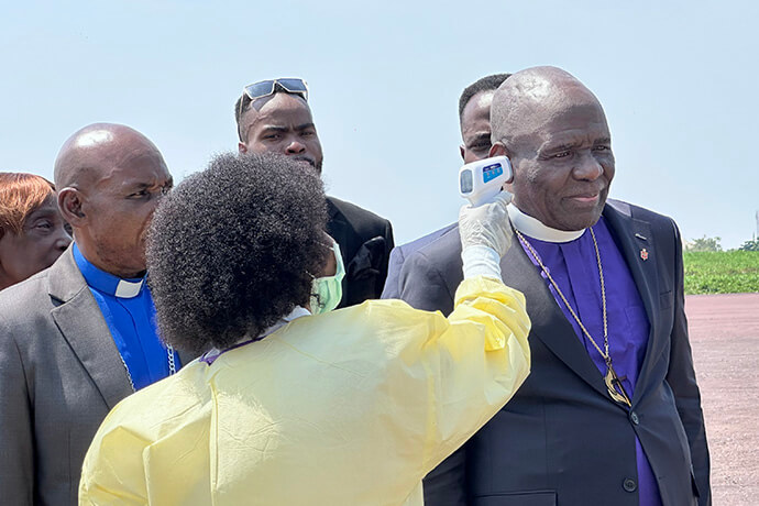 Bishop Antoine Kalema Tambwe has his temperature taken with an infrared thermometer by a health worker upon his arrival on the tarmac at Kindu National Airport. This rigorous screening illustrates the increased health surveillance at the country’s entry points, as The United Methodist Church steps up its integrated response to the spread of the 17th Ebola outbreak in Congo. Photo by Chadrack Tambwe Londe, UM News.